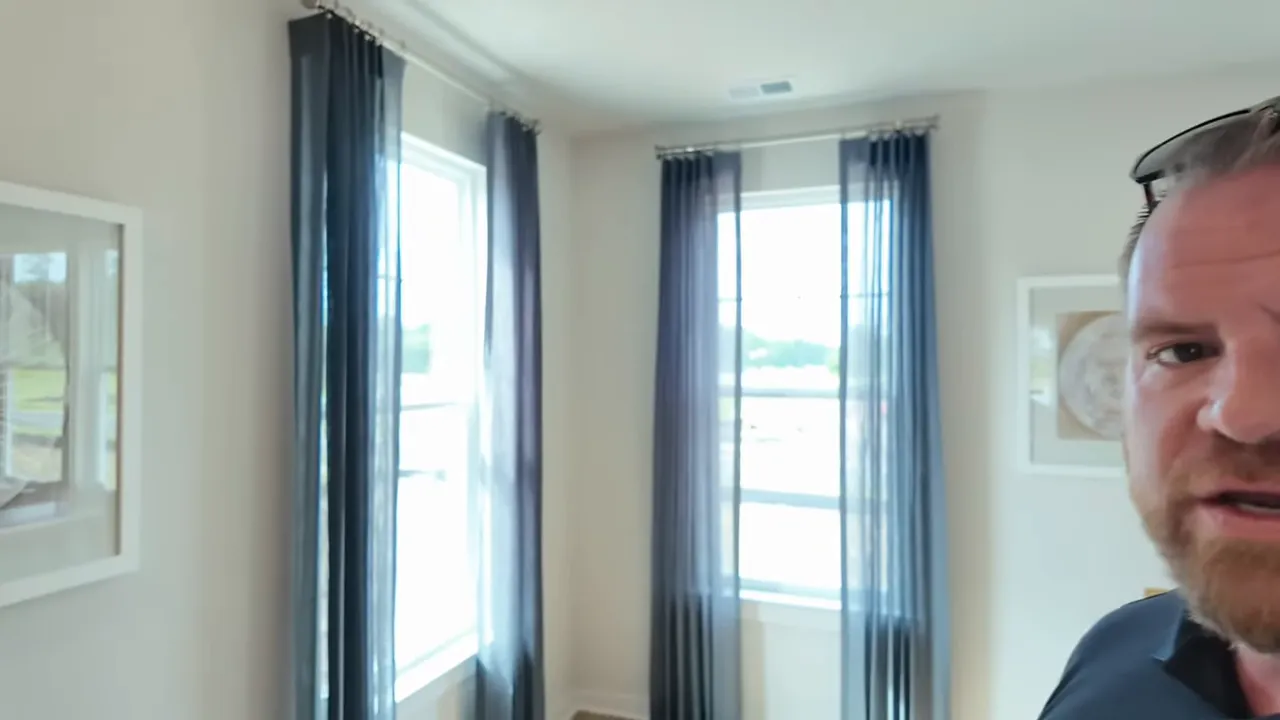 Bright townhouse interior corner with two tall windows and sheer curtains showing natural light