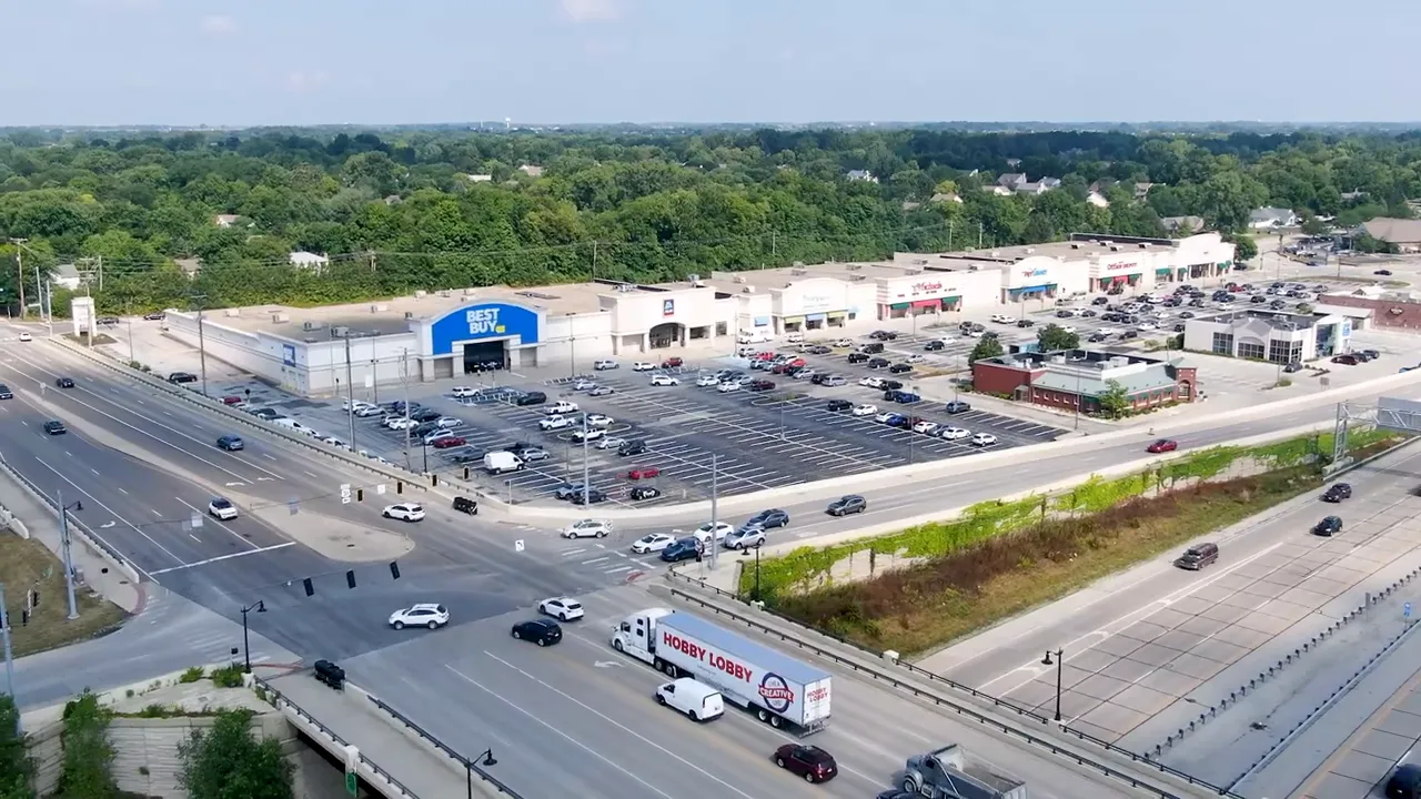Aerial view of busy commercial intersection with large stores parking lots and highway traffic