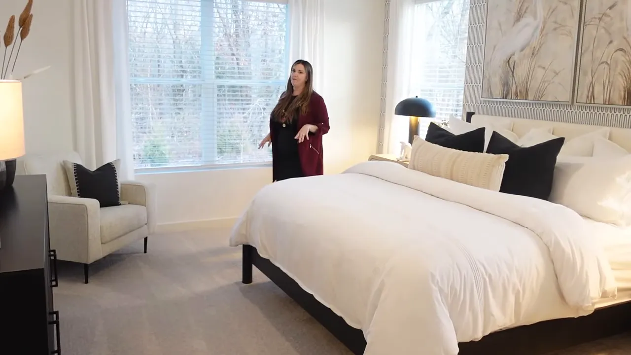 Large primary bedroom with white bed seating area and wide windows