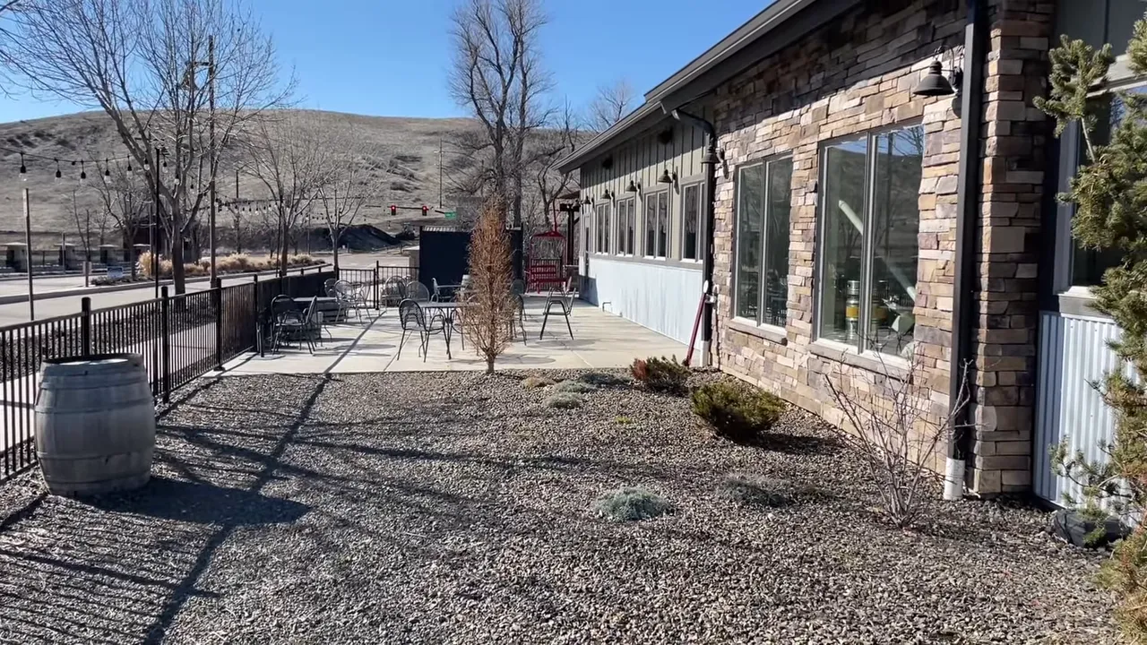 Outdoor patio with tables and chairs and a stone façade of a community restaurant in Avimor.