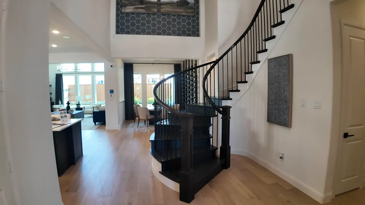 Open foyer with curved staircase leading toward kitchen and living area