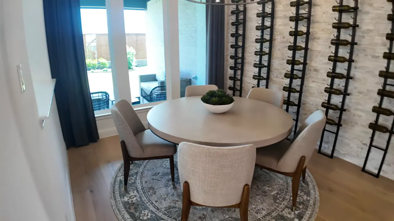 Round dining table beside tall wall mounted wine racks and glass doors