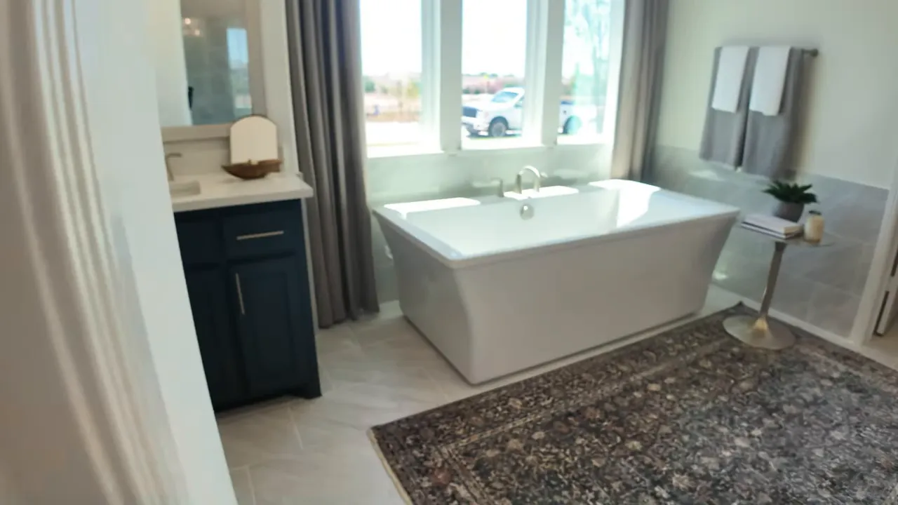 Primary bathroom with freestanding tub, large rug, and dual vanity cabinets