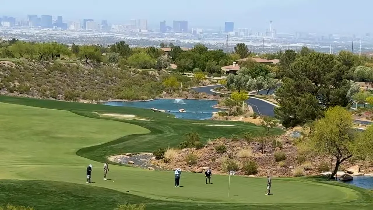 Golf course with players lakes desert landscaping and distant Las Vegas skyline