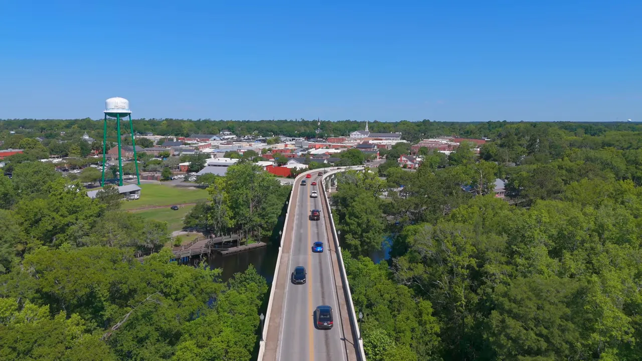 Aerial view of bridge leading into Conway with water tower, river and downtown buildings