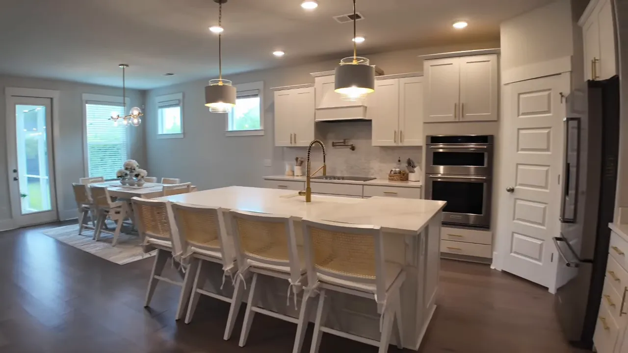 White kitchen with large island pendant lights and built in appliances