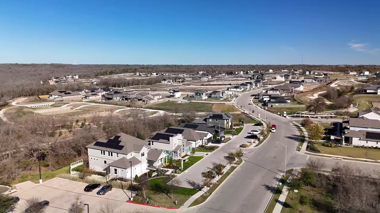 Drone aerial view of an Austin suburb with new-construction homes, streets, and green space