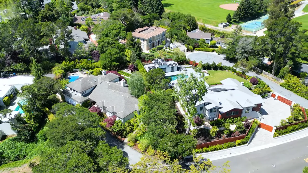 Aerial neighborhood view with multiple homes, pools and green spaces in San Mateo County