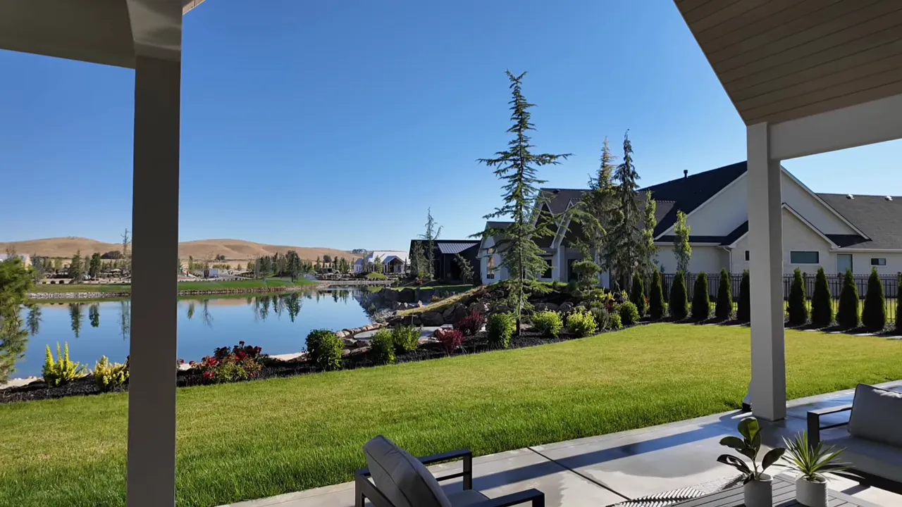 Lake view from covered patio with green lawn and landscaped shoreline