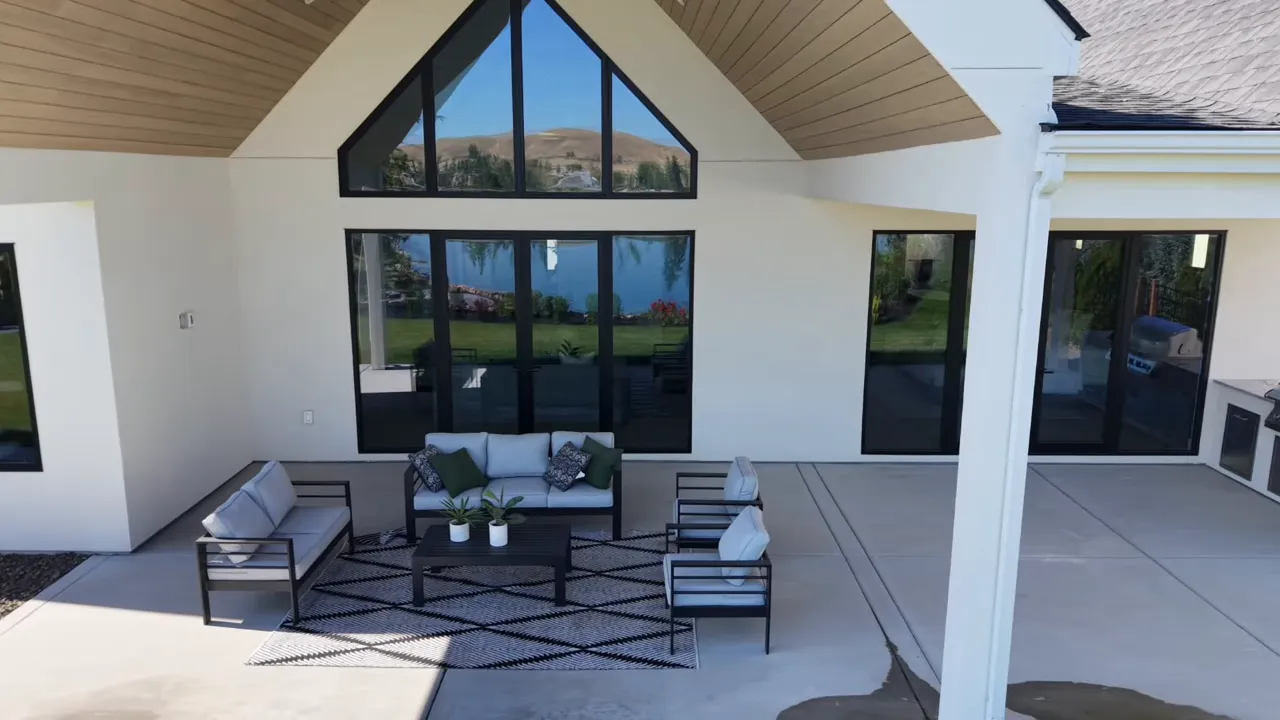 Covered patio with outdoor seating beneath tall gabled roof and large glass doors