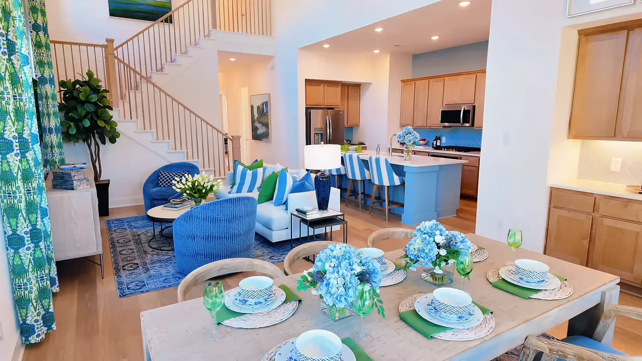 Dining table set beside open living room kitchen and staircase