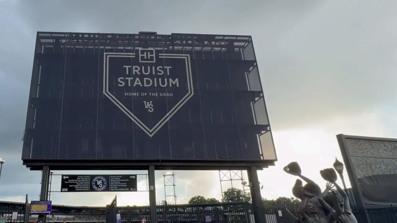 Truist Stadium scoreboard above a crowd under cloudy skies