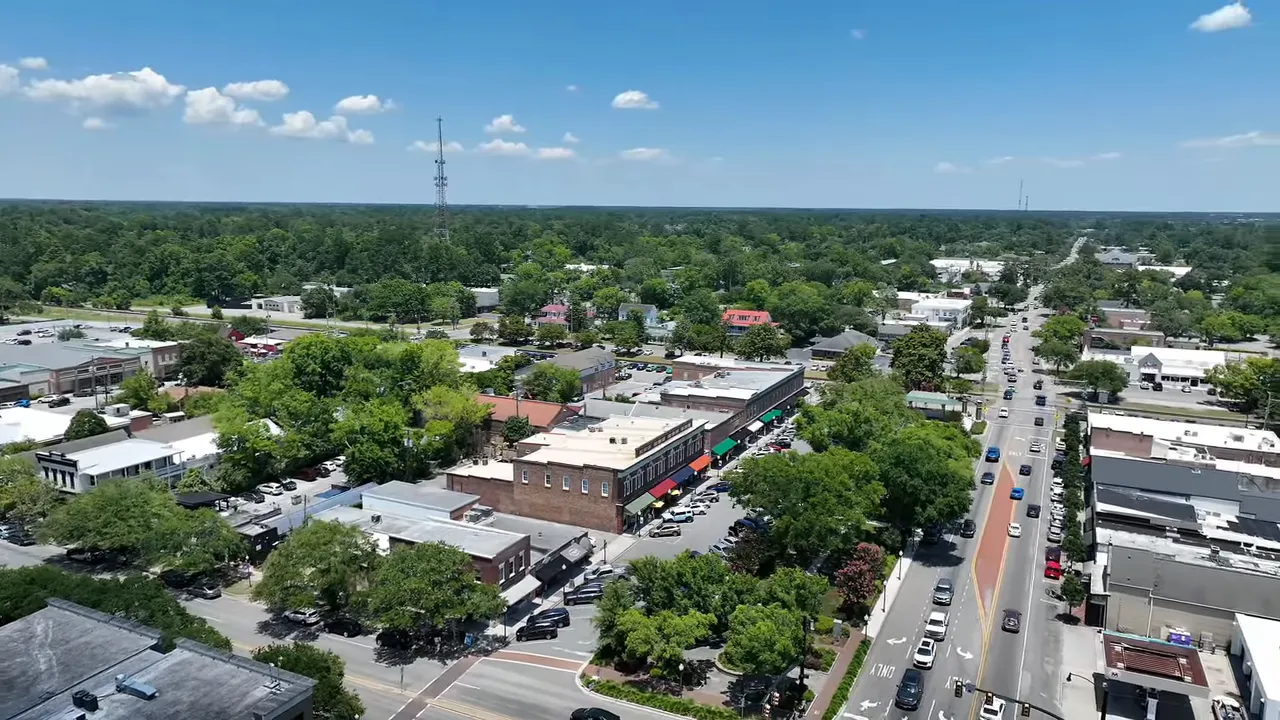 Wide drone shot of Summerville downtown showing streets, storefronts and surrounding trees