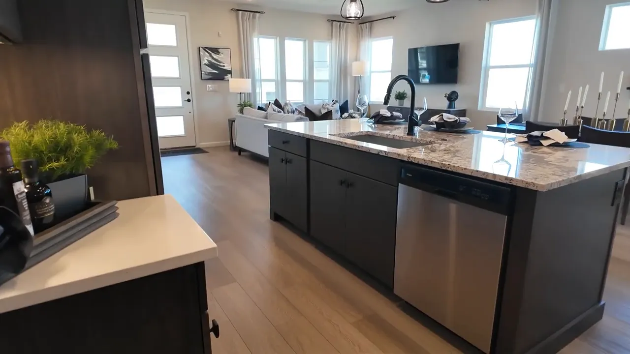 Aurora Highlands second model kitchen with large granite island and dark cabinetry