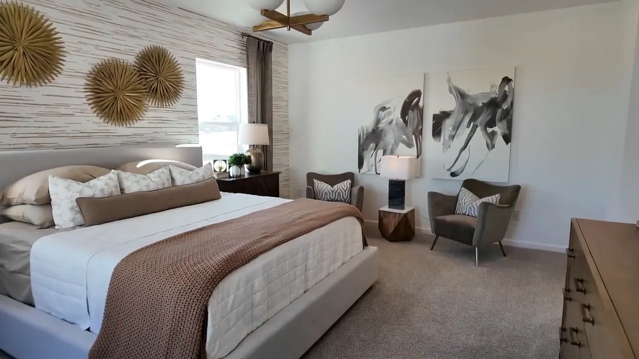 Primary bedroom lounge area inside Tri Pointe home at Aurora Highlands with wall art and reading chair