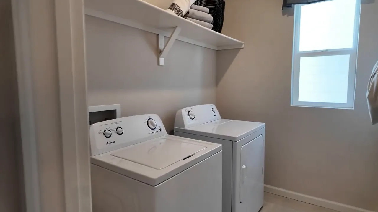 Upstairs laundry room built-in cabinetry with washer and dryer in Tri Pointe Aurora Highlands