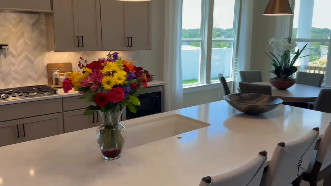 Large white kitchen island with gray cabinets and tall windows