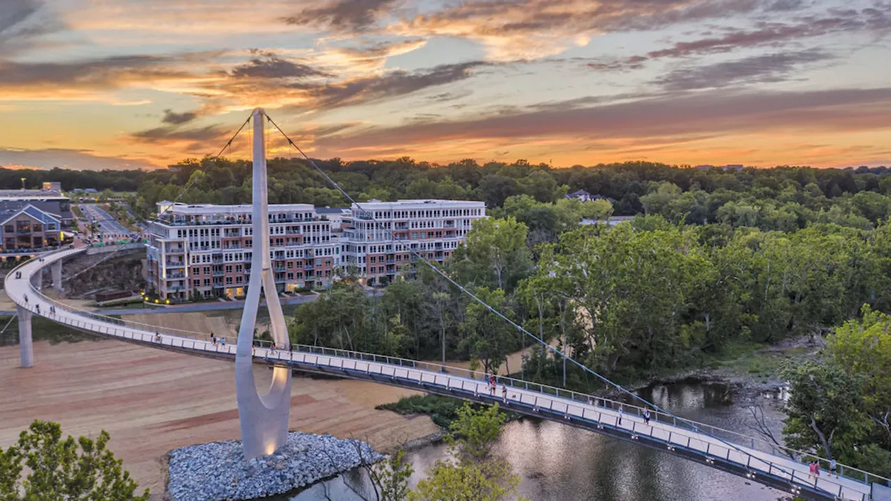 Pedestrian bridge over water with mixed use buildings at sunset