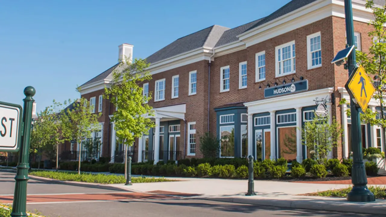 Brick commercial building with white columns and storefronts along a street