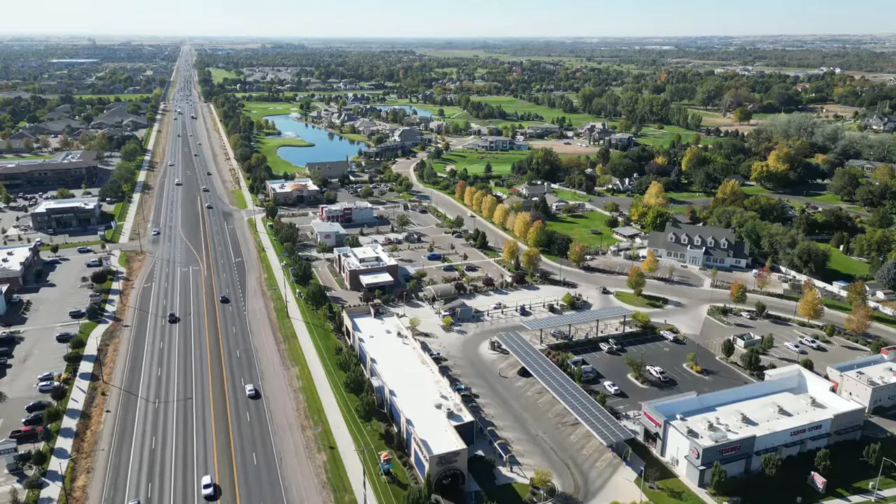 Aerial view of a long multi-lane road with adjacent retail, green spaces and residential areas in Meridian, Idaho