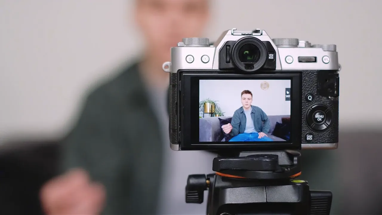 Camera on tripod recording a person speaking in the background