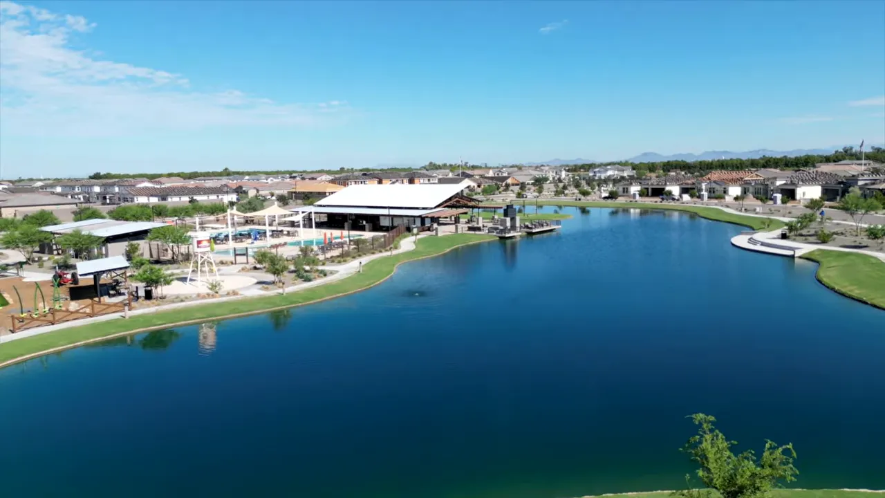 Aerial view of a community lake with homes and amenities around it
