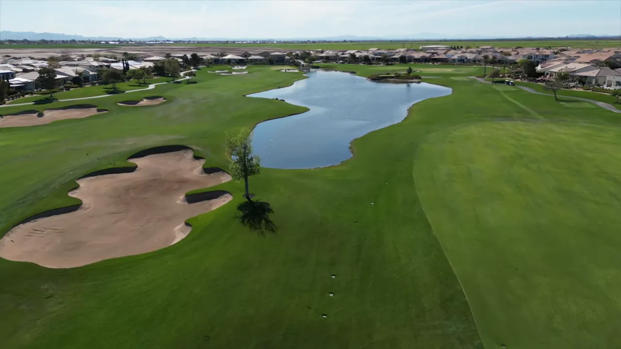Aerial view of a golf course with water features and nearby homes