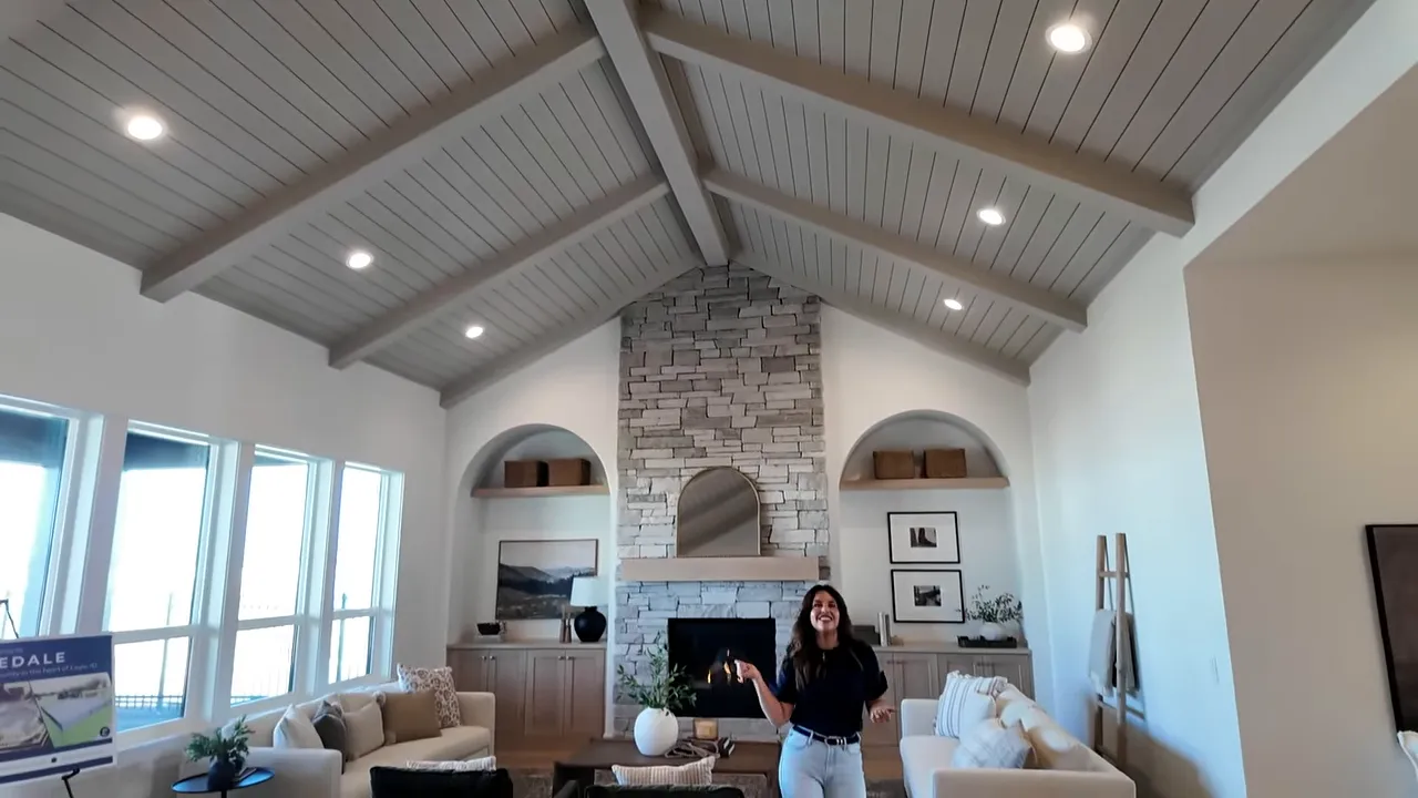 Wide view of great room with vaulted ceiling stone fireplace and built in shelving
