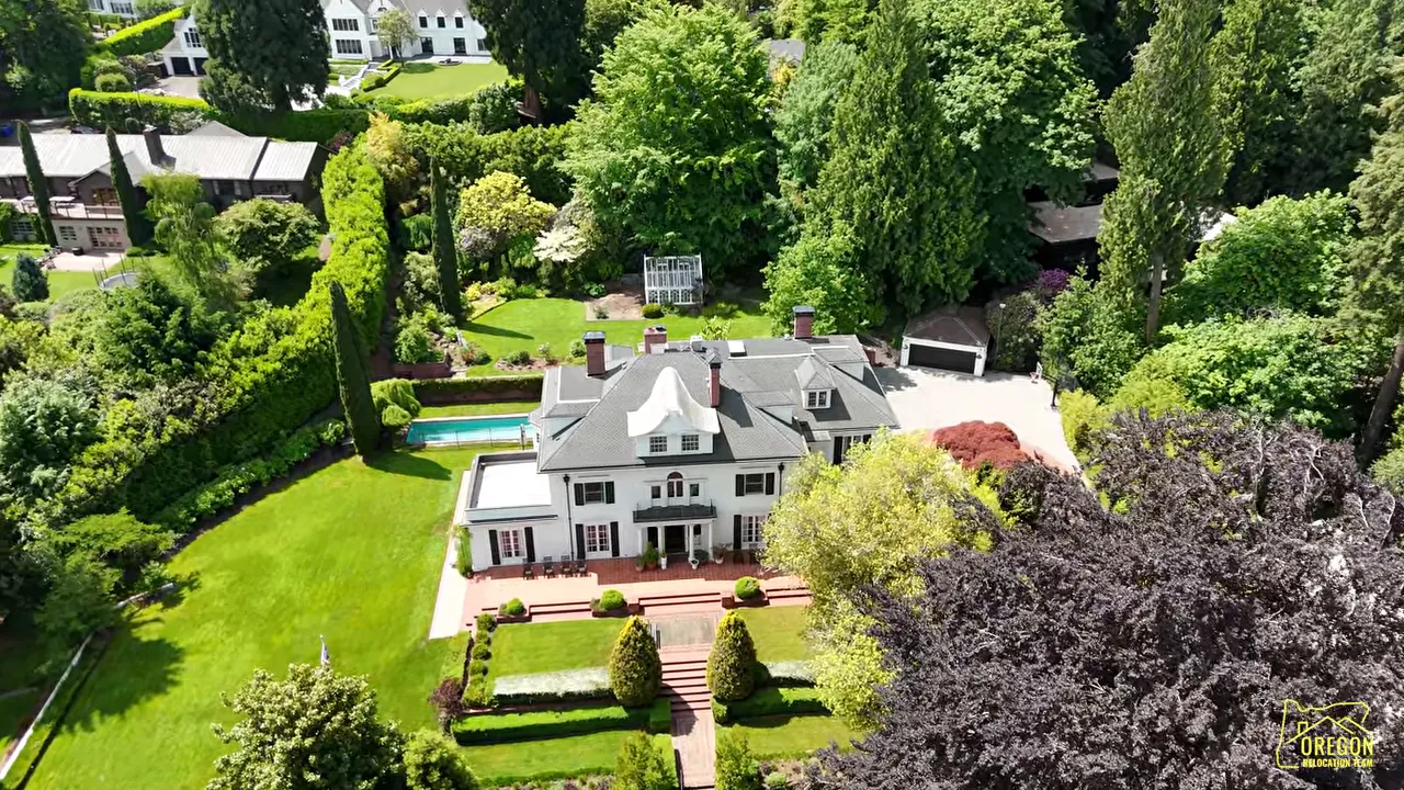 Aerial view of large traditional home with formal backyard hedges lawn and pool