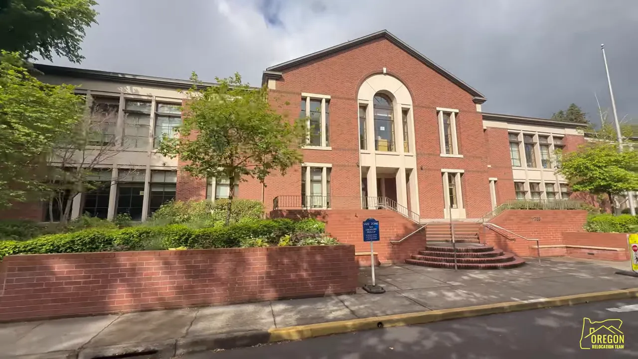 Brick school building with central arched entrance and steps from the street