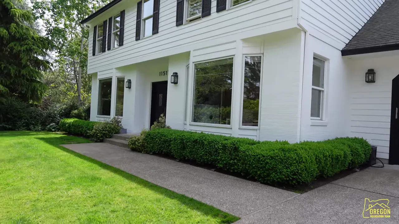 White traditional two story home with black shutters walkway and trimmed hedges