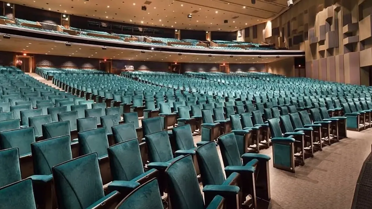 Interior of a large theater with rows of teal seats