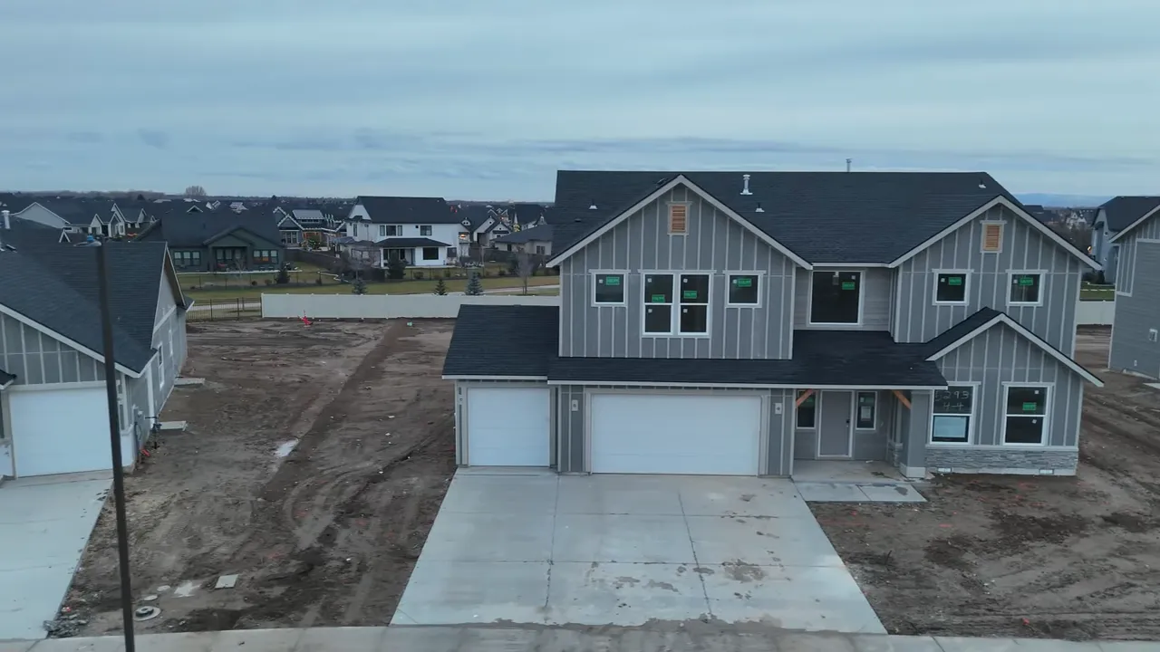 Aerial front view of a new two-story CBH home with driveway, garage, and neighboring houses and yards in the Eagle neighborhood