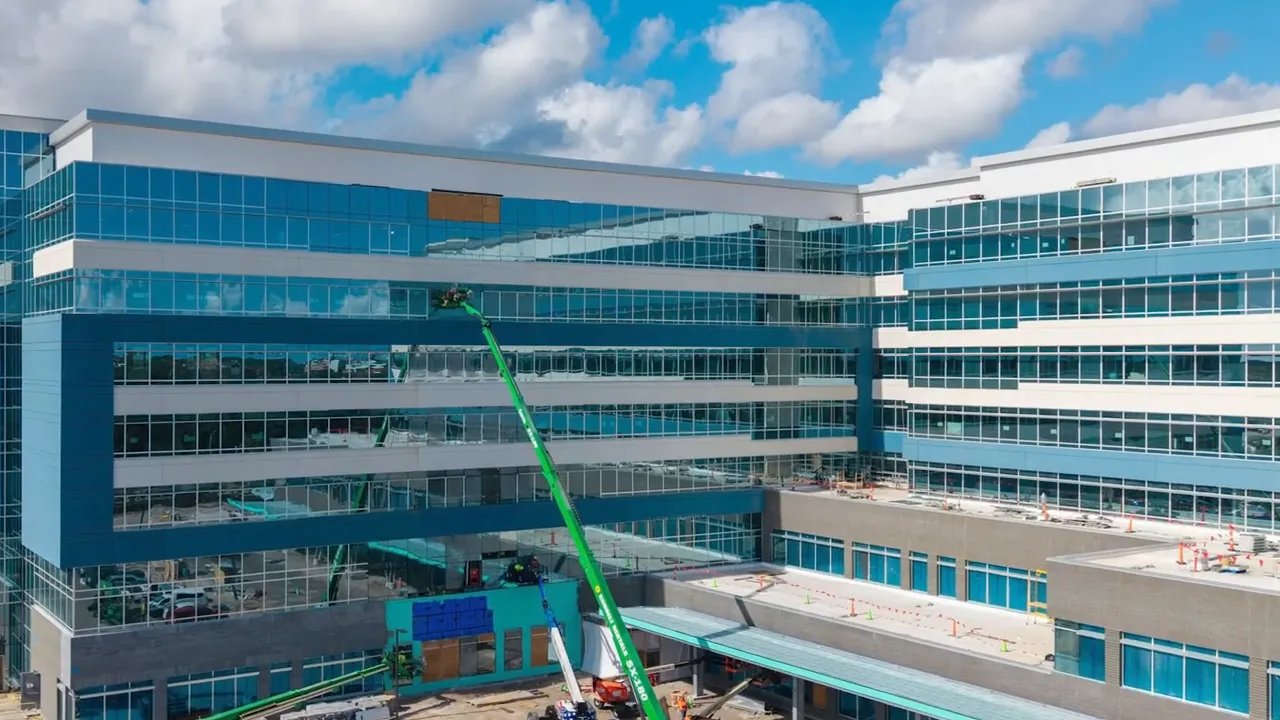 Exterior view of a modern multi story hospital building with parking lot in front