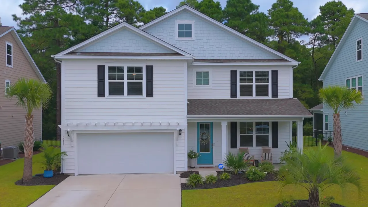 Front view of white two story home with palm trees and front porch