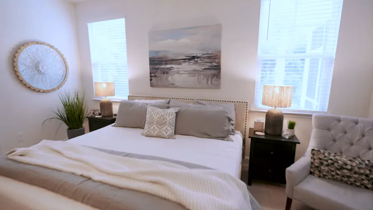 Large primary bedroom with king bed seating and windows