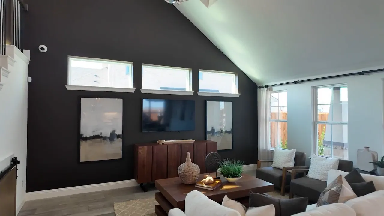living room with dark accent wall, three clerestory windows, TV console and seating in model home