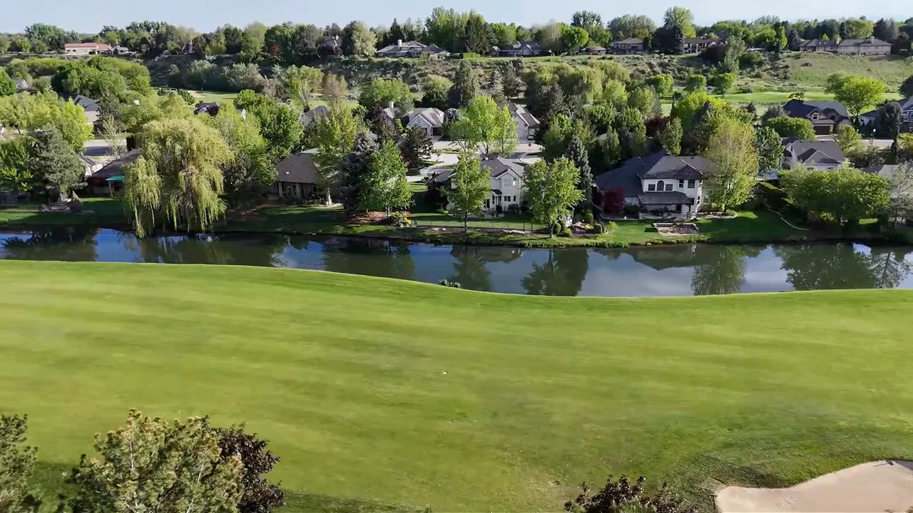 Aerial view of an Idaho subdivision with a pond, green landscaping, and surrounding homes