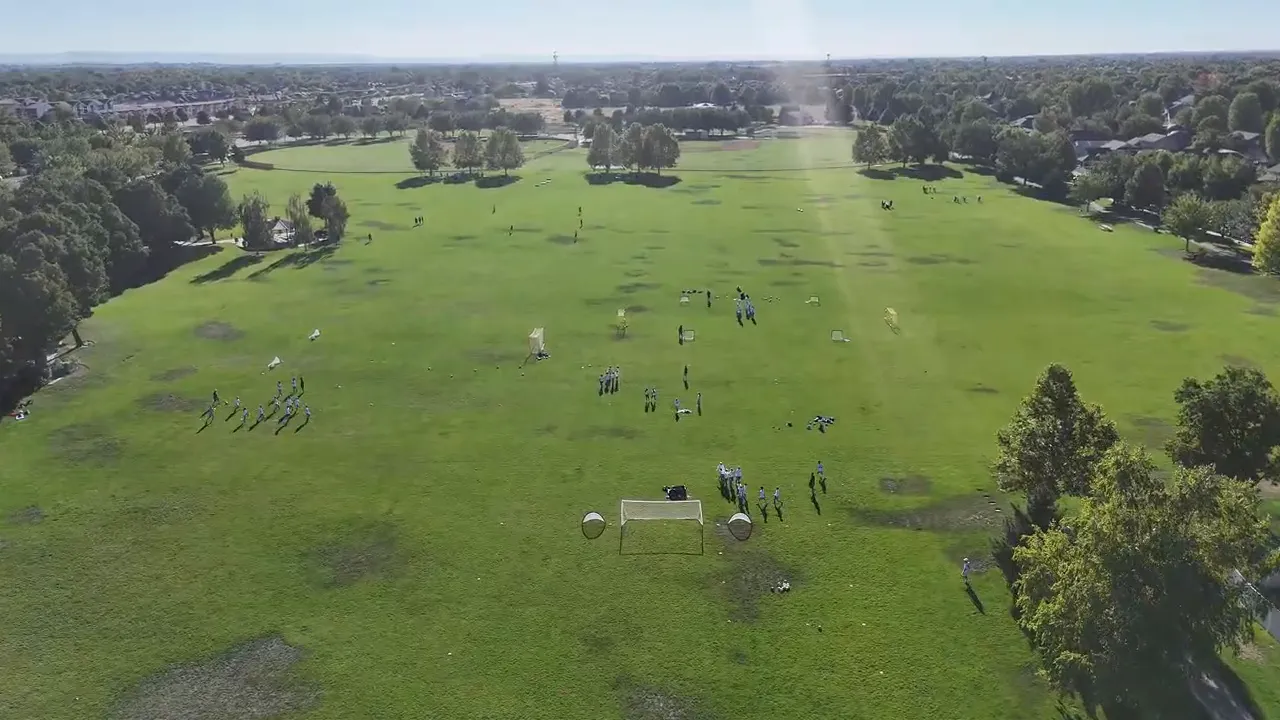 Aerial view of a large grassy field with groups and equipment set up for outdoor activities