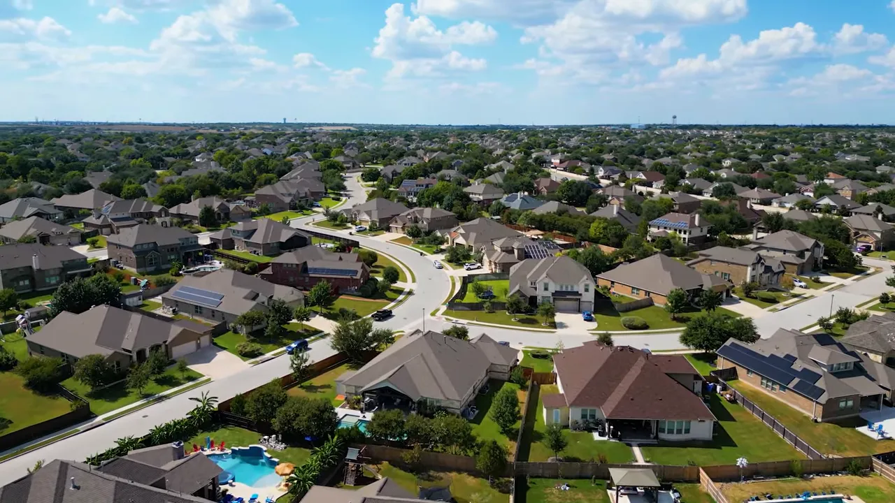 Aerial shot of suburban neighborhood with curved streets, yards, and a backyard pool