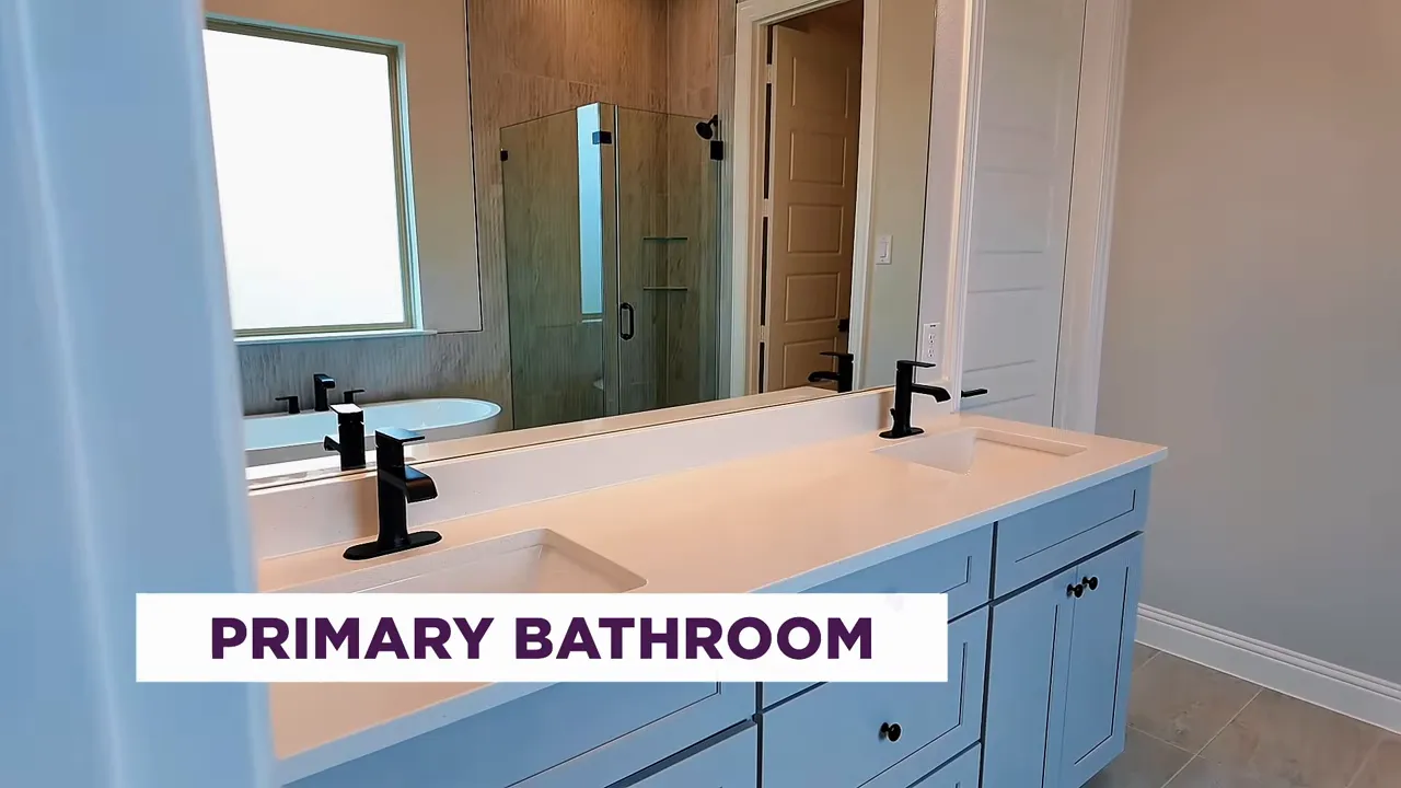 Primary bathroom double vanity with modern fixtures and frameless shower in Frisco new construction home