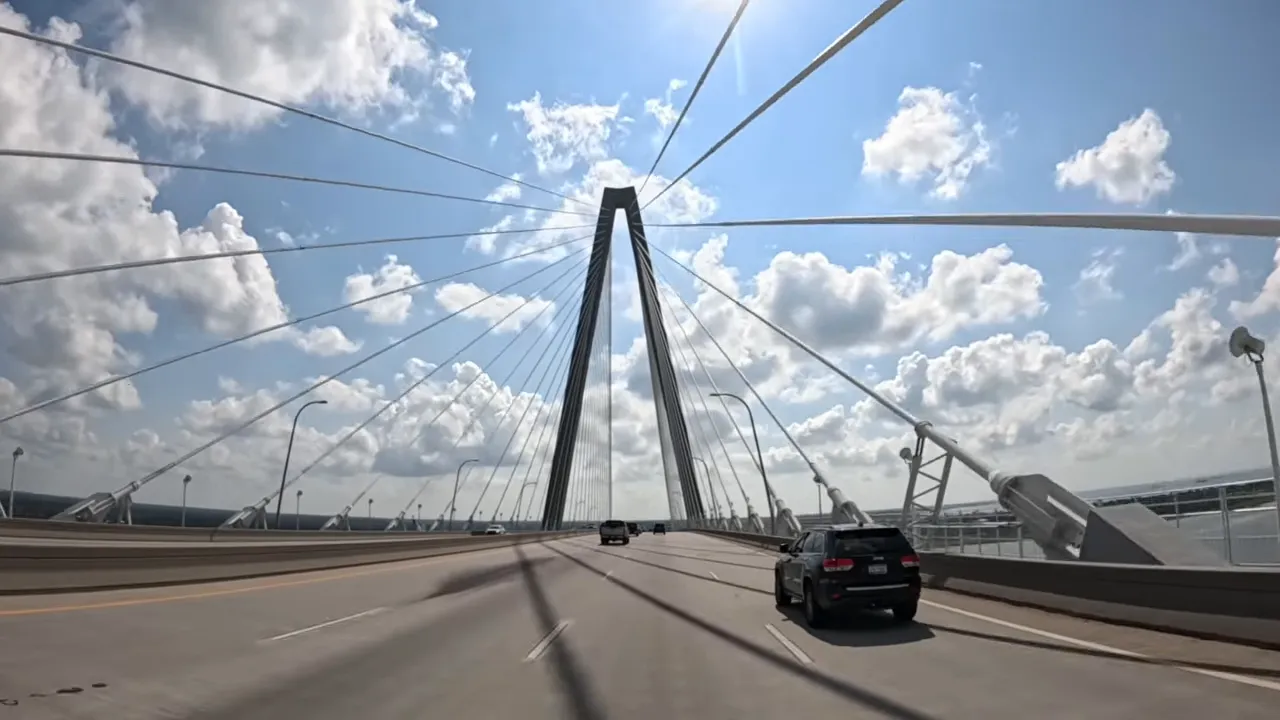 Suspension bridge roadway and cables with cars traveling, illustrating bridge commute bottlenecks near Charleston