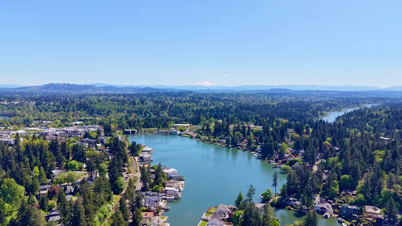 Aerial view of a Portland-area neighborhood along a river with surrounding hills and homes