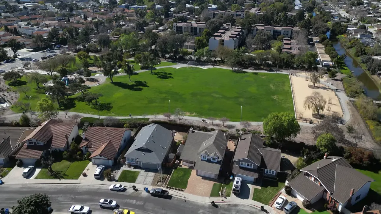Aerial view of a large green park field surrounded by nearby homes