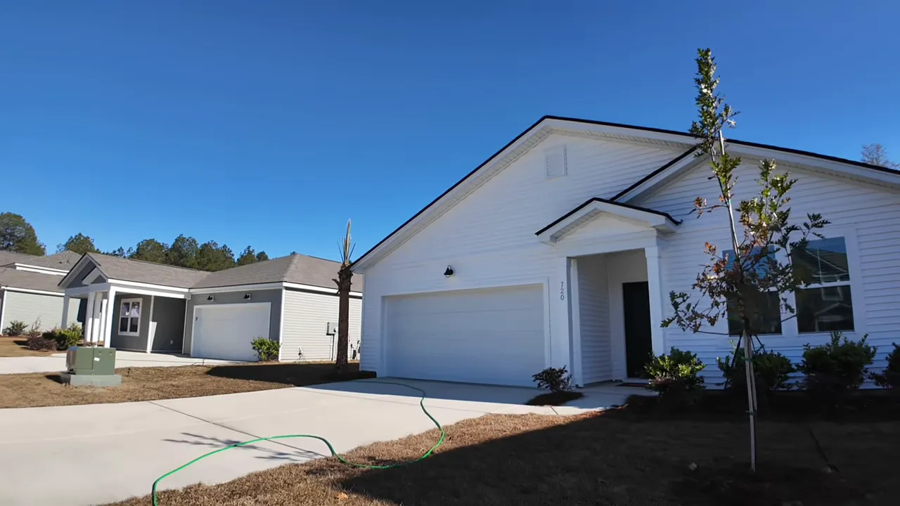 front exterior of a white single-story ranch home with two-car garage, small porch and young landscaping