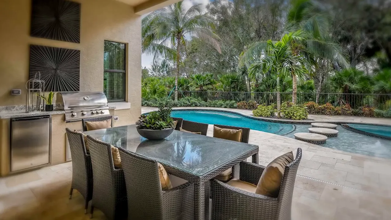 Patio dining area overlooking a backyard swimming pool at Artistry Palm Beach