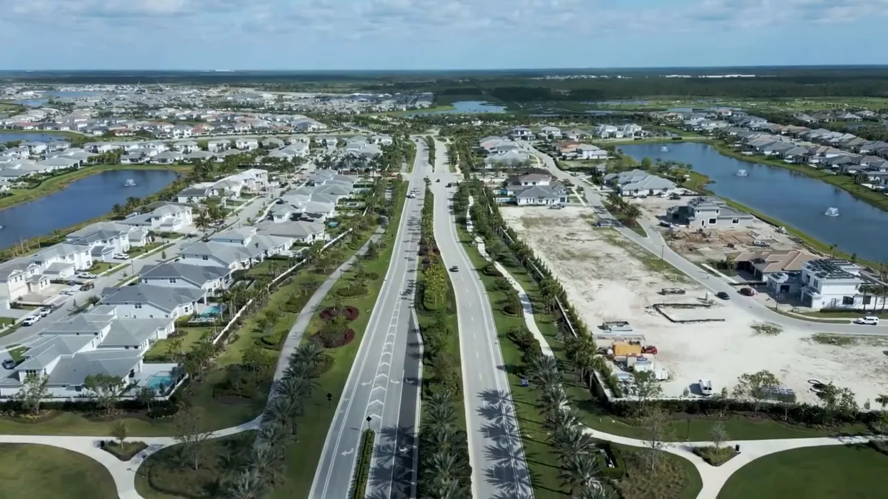 Aerial view of a planned Palm Beach Gardens community with lake, streets, and completed homes