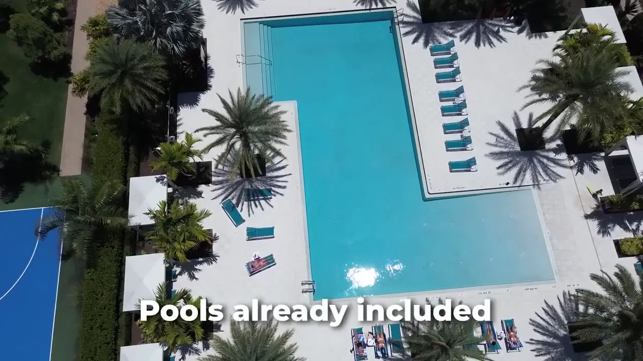 Aerial view of a finished swimming pool area with tropical landscaping and patio seating
