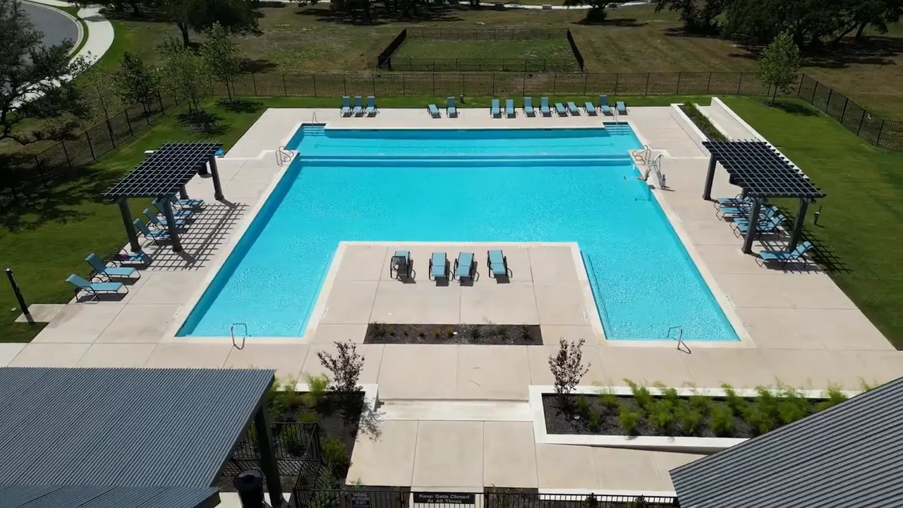 Aerial view of community pool clubhouse and surrounding neighborhood streets