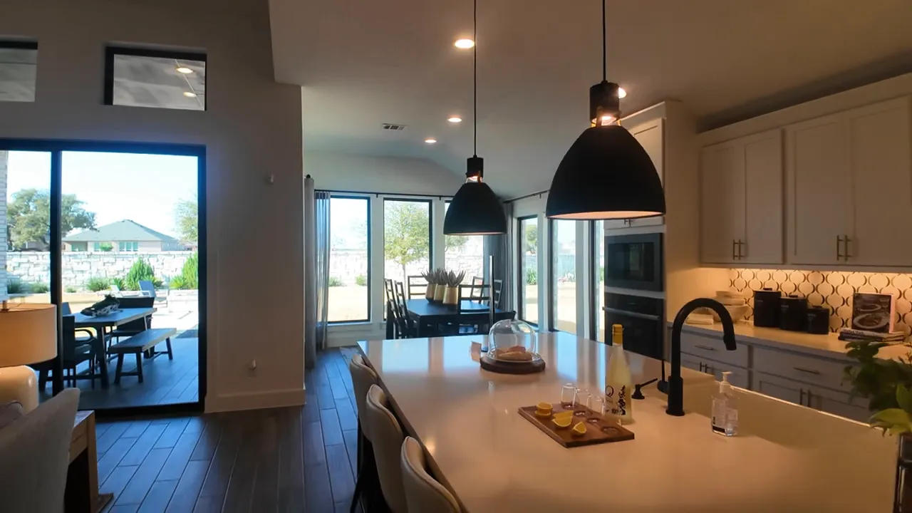 Kitchen island with pendant lights bar stools and surrounding cabinets